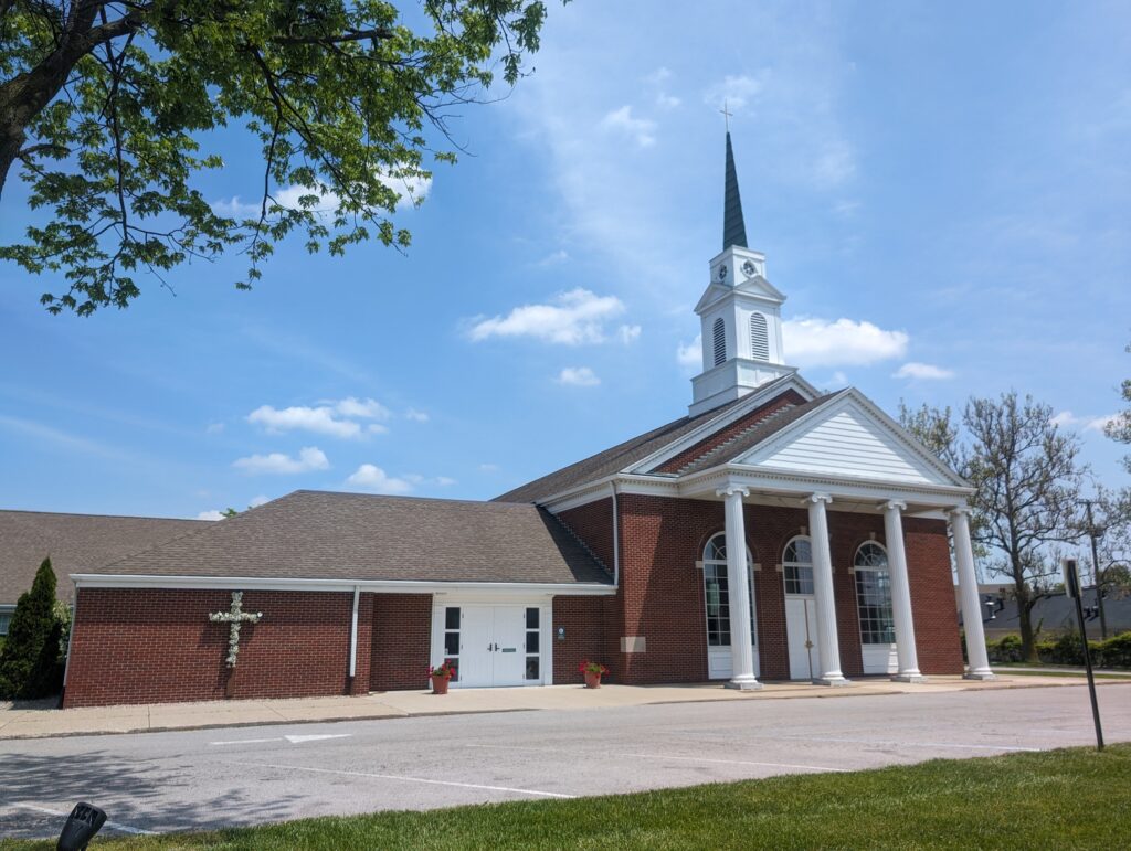 A brick church with four tall, white pillars and a steeple.