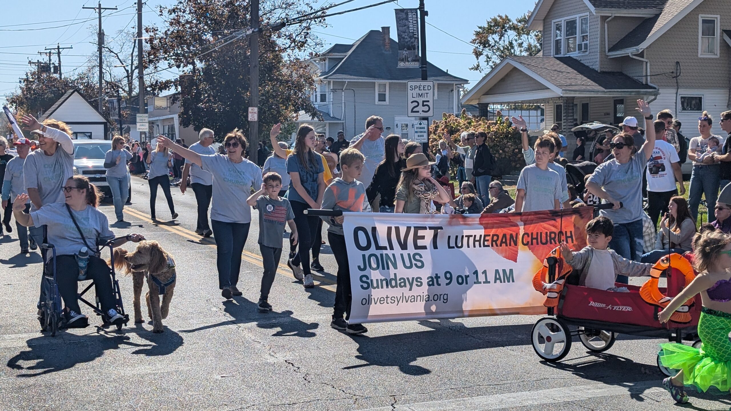 Group walking in a parade carrying a banner displaying "Olivet Lutheran Church"