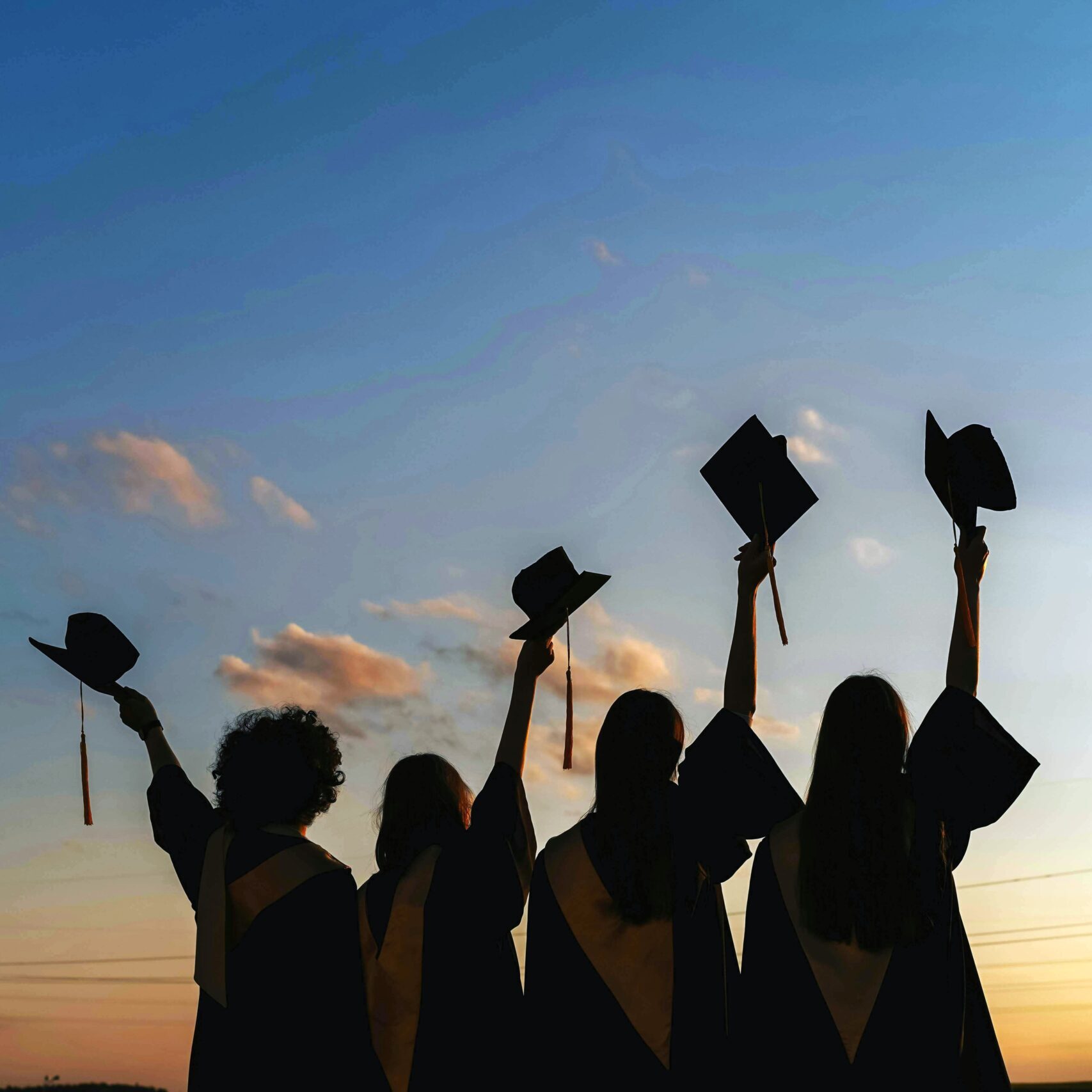 Group of graduates hold up their graduation caps