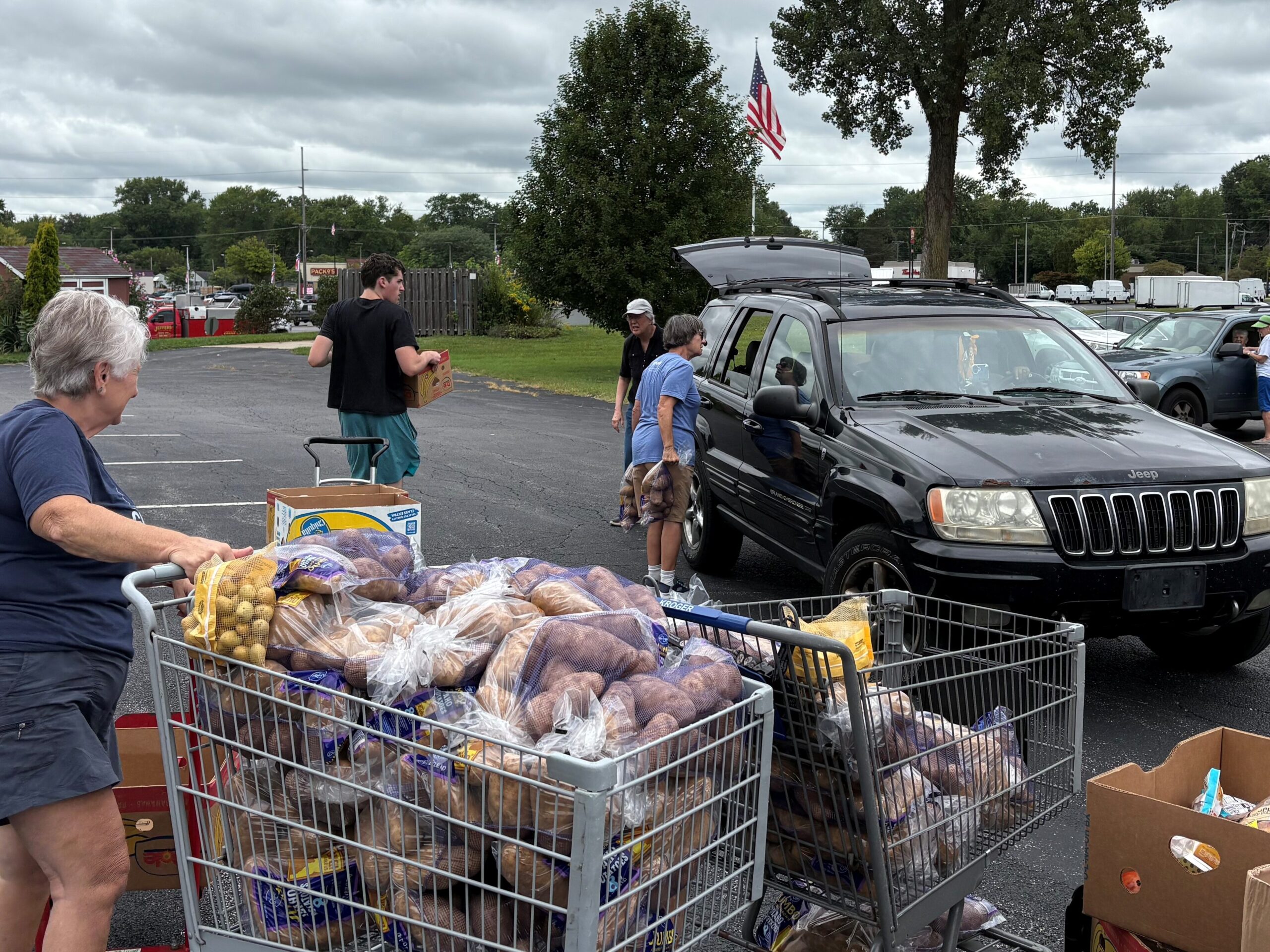 Volunteers load food into cars during a community food distribution in a parking lot.
