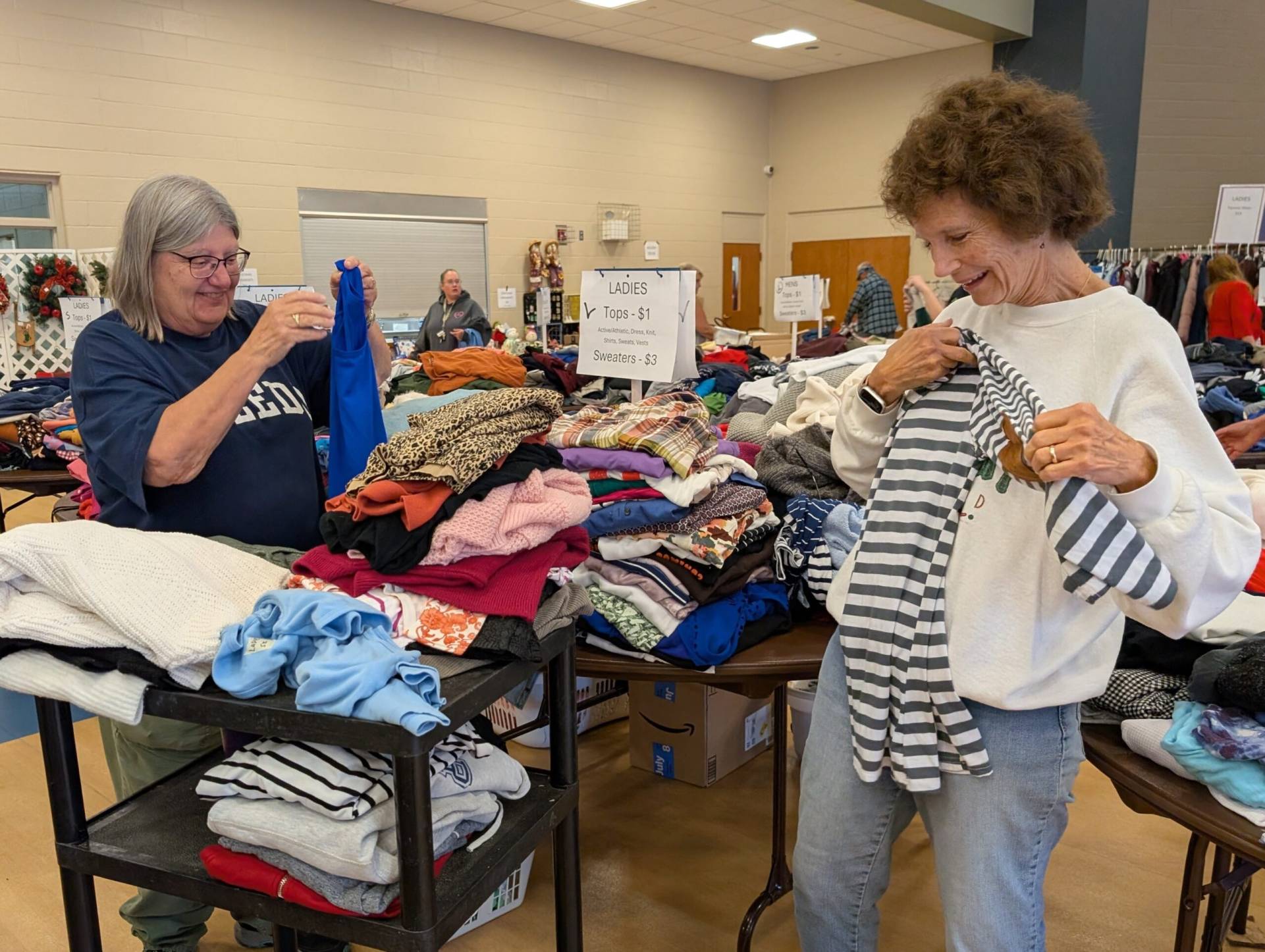 Two volunteers fold clothing during a church rummage sale